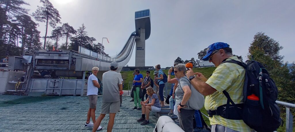 spannende Führung an der weltbekannten Sprungschanze: Wir stehen am Schanzentisch und lauschen den wissenswerten Ausführungen zweier Skispringer - 12.09.2023